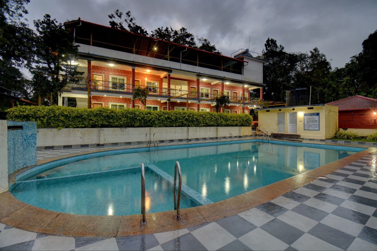 Night lights reflecting on the calm pool surface next to resort building